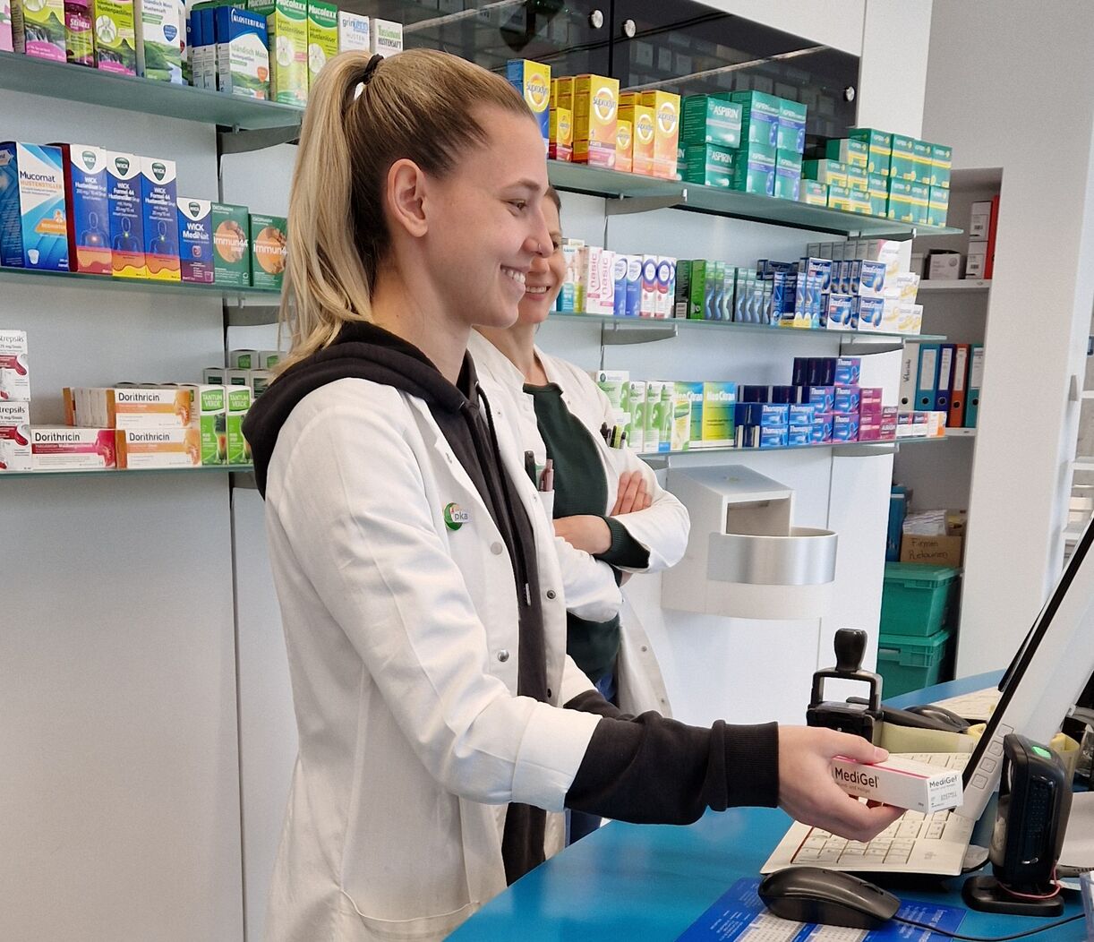 Frau am Apothekenpult bei Scannen eines Apothekenproduktes