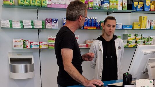 Zwei Personen im Gespräch am Apothekenverkaufspult