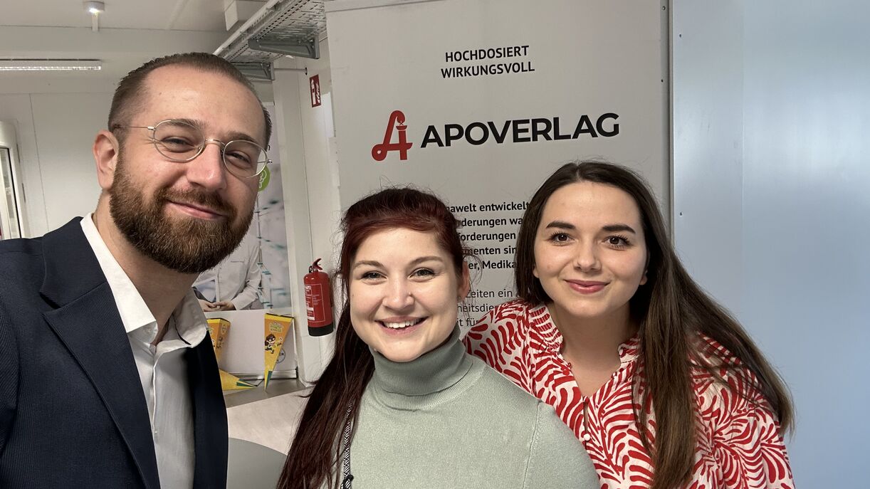 Personen vor einem Roll-up stehend in die Kamera lächelnd