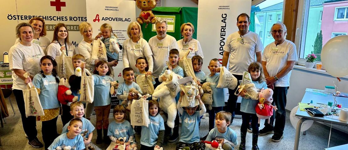 Brunner Teddyklinik Gruppenfoto mit den Kinderrucksäcken und den mitgebrachten Stofftieren - Gruppenfoto in der Bezirksstelle des Roten Kreuzes in Brunn am Gebirge. Die Kinder halten ihre mitgebrachten Stofftiere und ihre Kinderrucksäcke in den Händen.