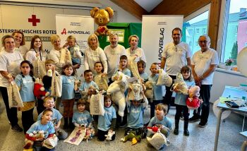 Brunner Teddyklinik Gruppenfoto mit den Kinderrucksäcken und den mitgebrachten Stofftieren - Gruppenfoto in der Bezirksstelle des Roten Kreuzes in Brunn am Gebirge. Die Kinder halten ihre mitgebrachten Stofftiere und ihre Kinderrucksäcke in den Händen.