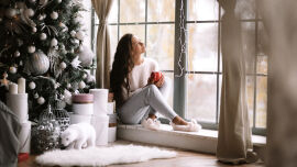Entspannte Frau sitzt am Fenster_Weihnachten_shutterstock_1240309276 - In der heutigen Zeit sind die Stressoren vor allem psychischer, emotionaler und leider auch chronischer Natur.